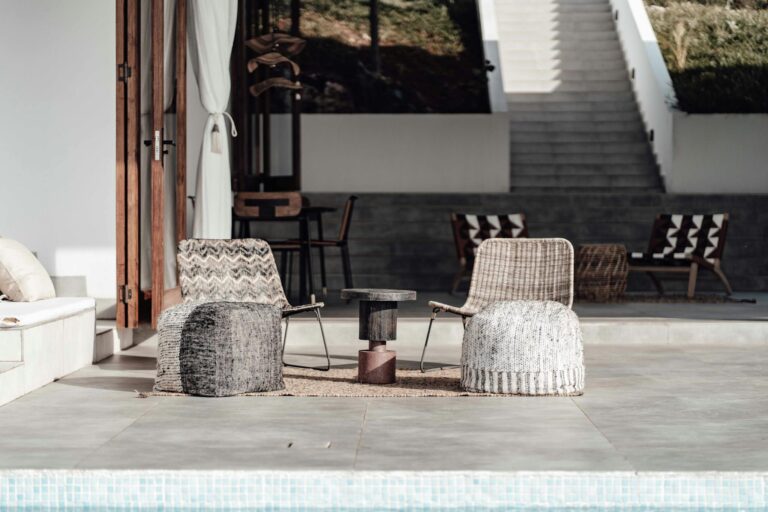 Luxurious outdoor seating arrangement by a pool, featuring modern chairs and decor in a minimalist style.