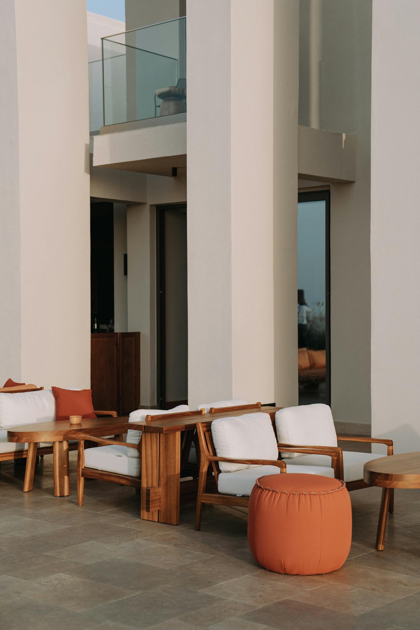 Stylish modern patio featuring elegant wooden furniture and cushions in a sunlit outdoor setting.