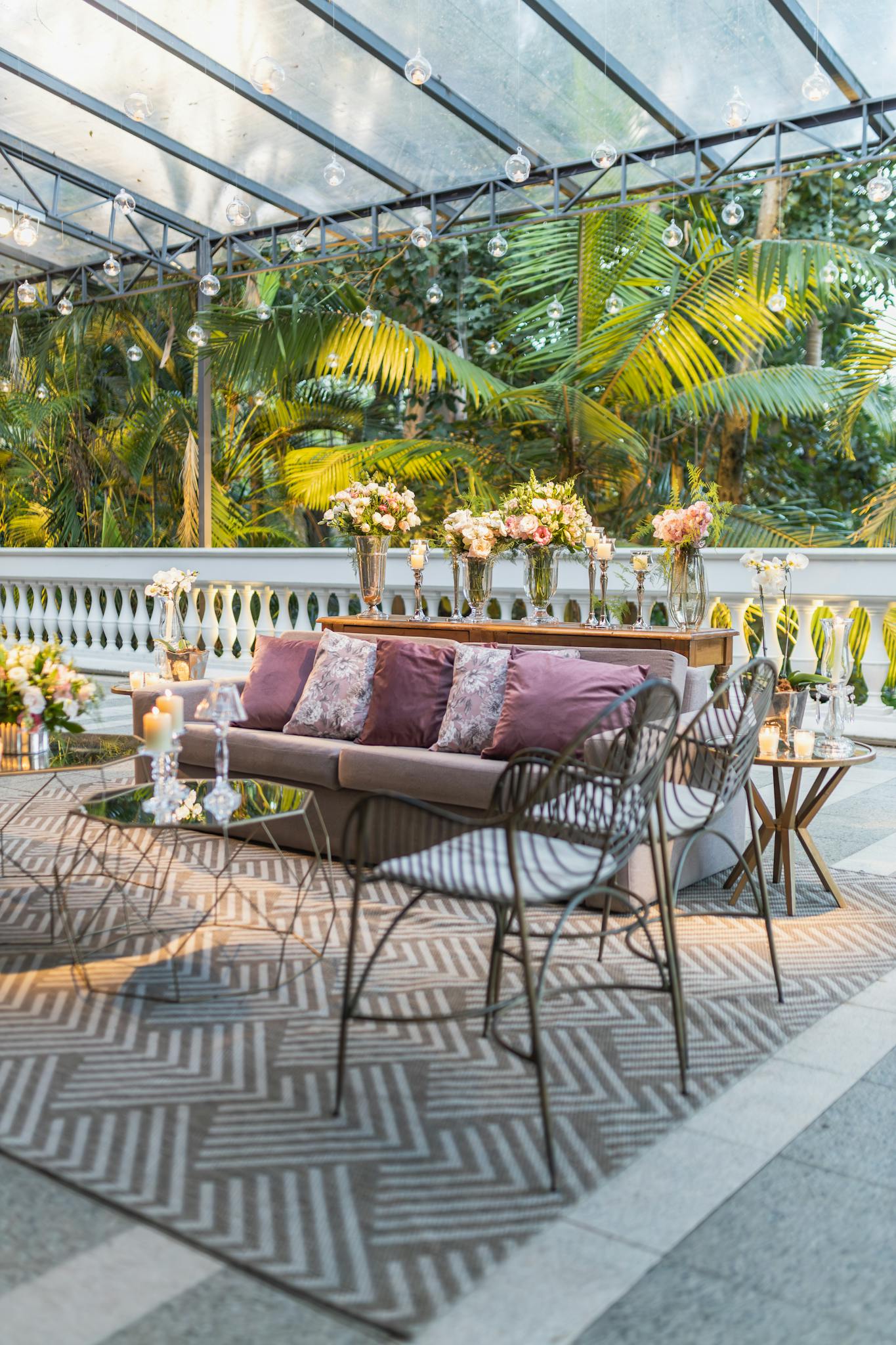 Stylish outdoor patio with seating, lush greenery, floral arrangements, and ambient lighting.